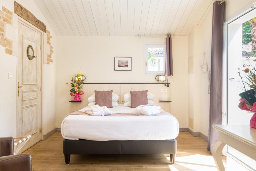 a bedroom with a bed with white sheets and pillows at Hôtel Restaurant & Spa Plaisir in Le Bois-Plage-en-Ré