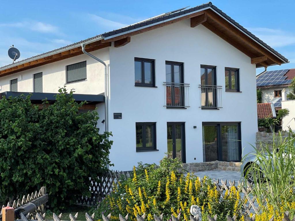 a white house with black windows and a fence at Ferienwohnung Matzing 