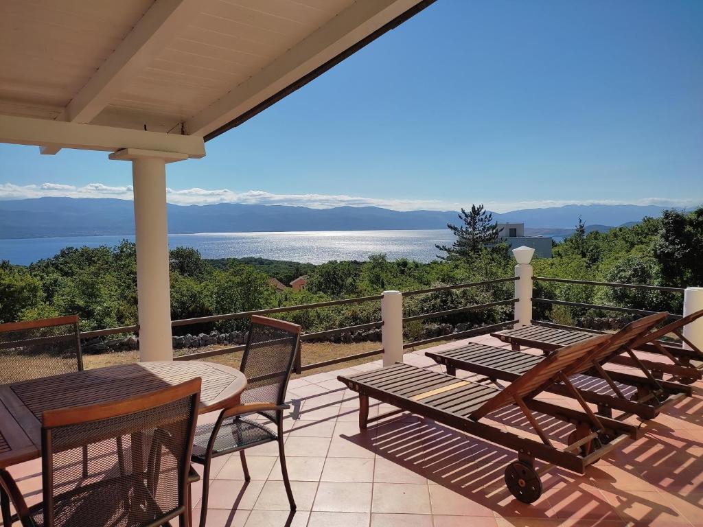 eine Terrasse mit Tischen und Stühlen auf dem Balkon in der Unterkunft Holiday Home with Sea View in Vrbnik