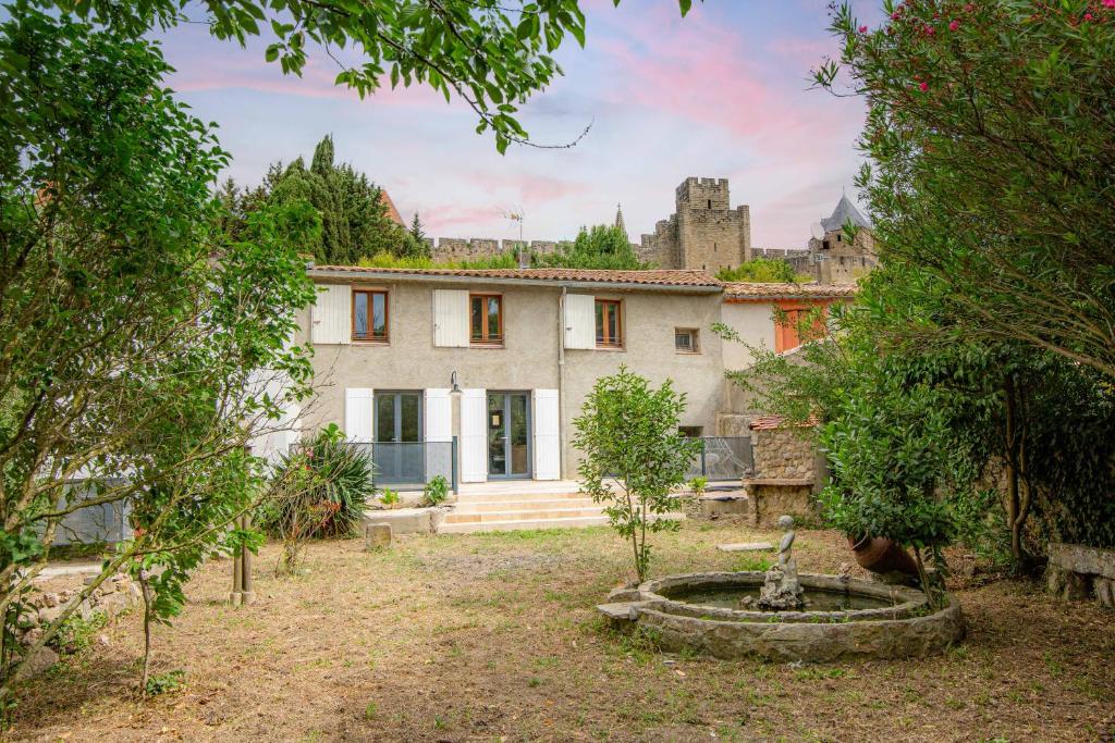 una casa con jardín y castillo en el fondo en Les Pimprenelles, en Carcassonne