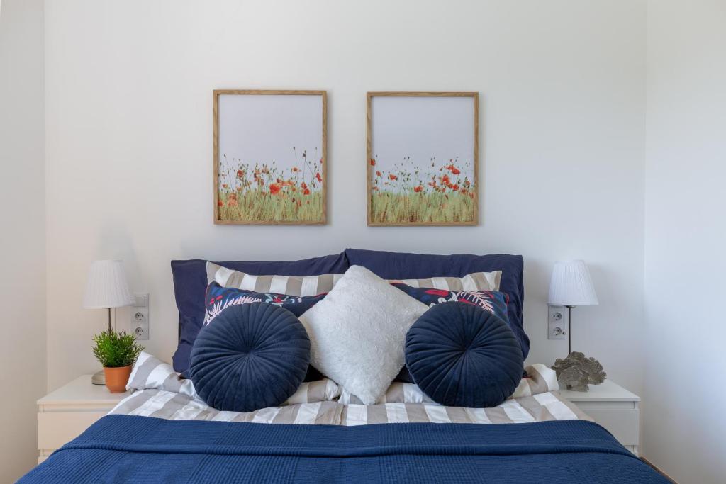 een slaapkamer met een blauw bed met twee foto's aan de muur bij Kalia Apartmanok in Mindszentkálla