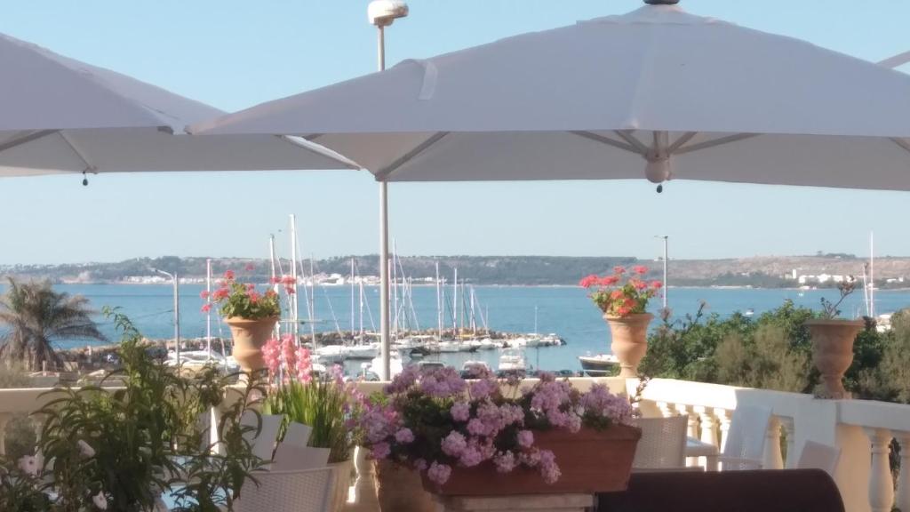 a patio with flowers and an umbrella and a harbor at Antico Palazzo Spinola in Gallipoli