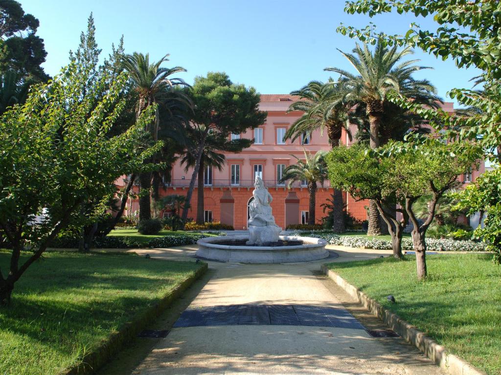 a fountain in front of a building with palm trees at Miglio d'Oro Park Hotel in Ercolano