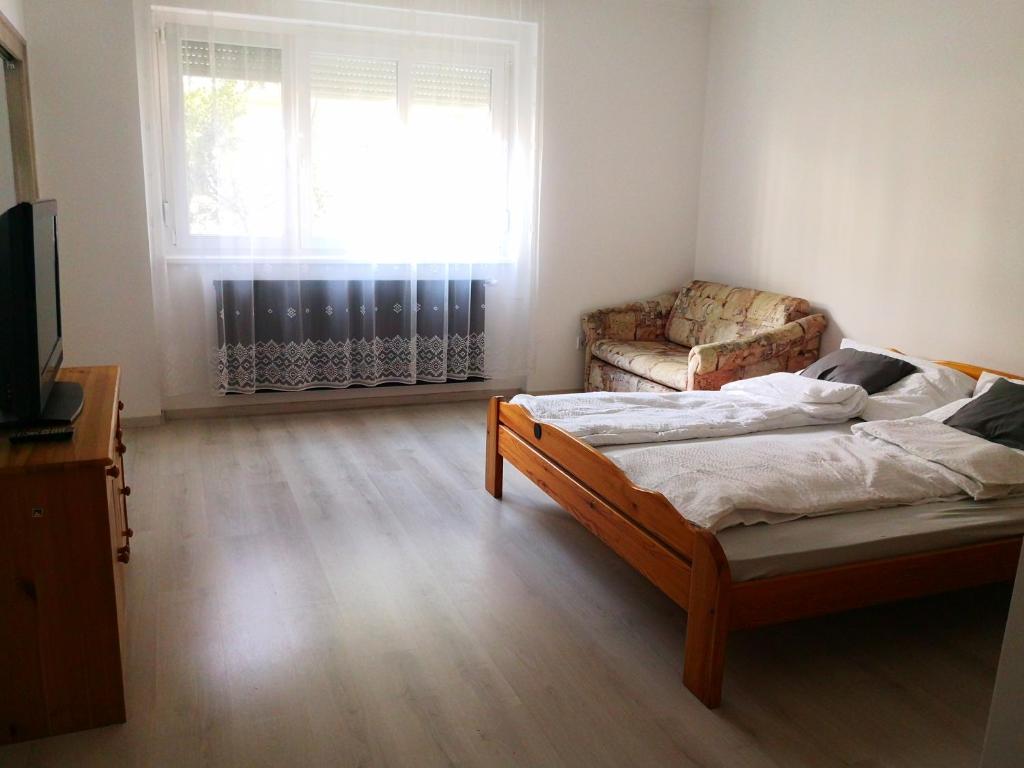 a bedroom with a bed and a couch and a window at OASIS APARTMAN II. in Szeged