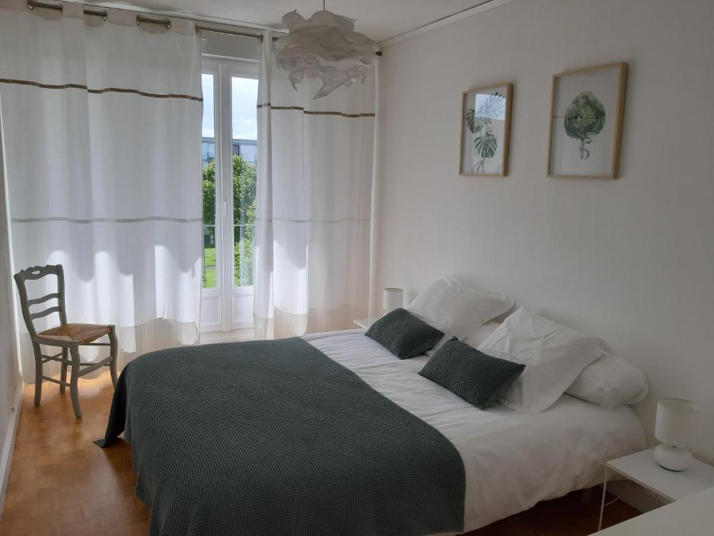 een witte slaapkamer met een groot bed en een stoel bij Appartement lumineux idéalement situé à proximité de musées équipements sportifs salle de spectacle commerces in Caen