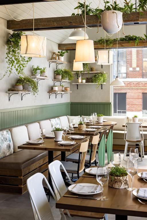 a restaurant with wooden tables and chairs and plants at 1 Hotel Toronto in Toronto