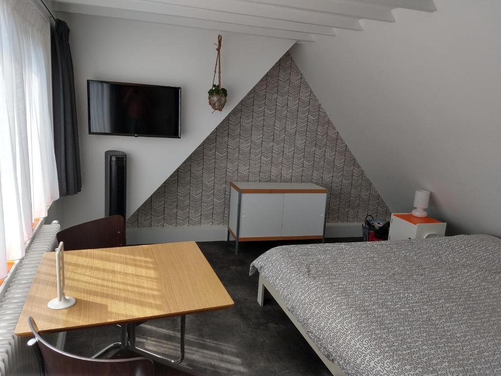a bedroom with a bed and a table and a tv at Hoogland aan Zee in Egmond aan Zee