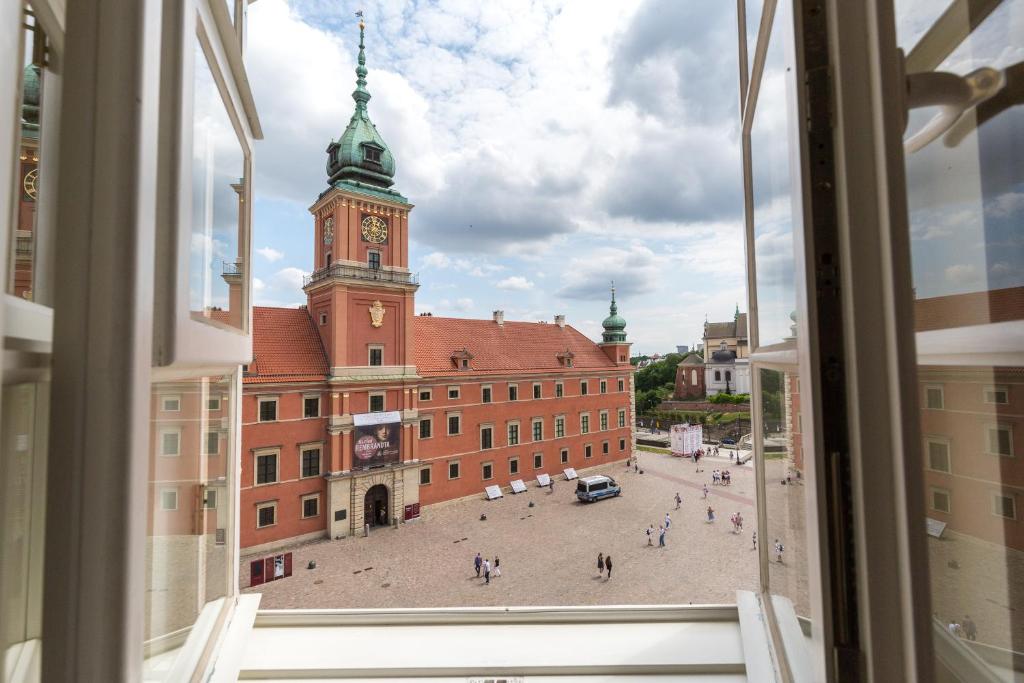 uma vista a partir de uma janela de um edifício com uma torre de relógio em Royal Castle Square Apartment Old Town Warsaw Warszawa em Varsóvia