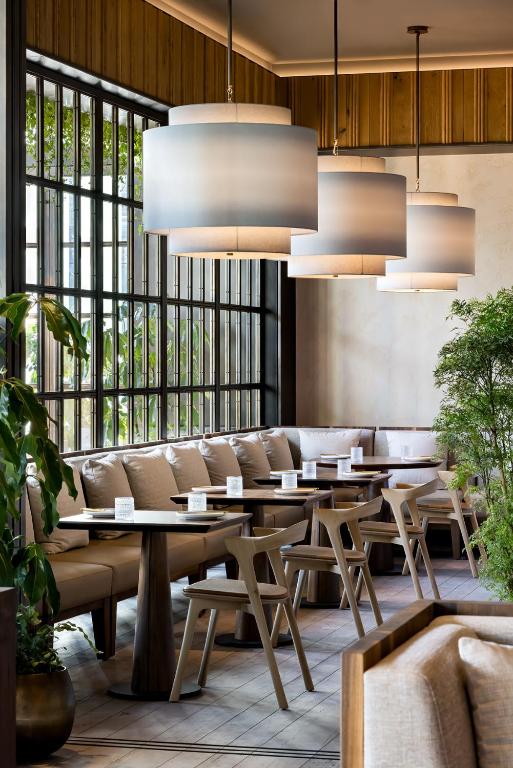 a restaurant with tables and chairs and large windows at 1 Hotel Toronto in Toronto