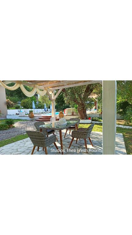 patio ze stołem i krzesłami pod parasolem w obiekcie Studios Thea Fresh Rooms Thassos w mieście Limenas