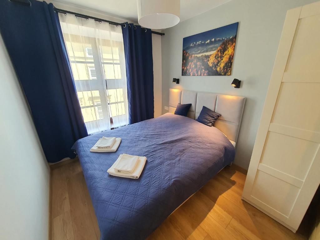 1 dormitorio con 1 cama azul y 2 toallas en Apartments Legendary Kraków, en Cracovia