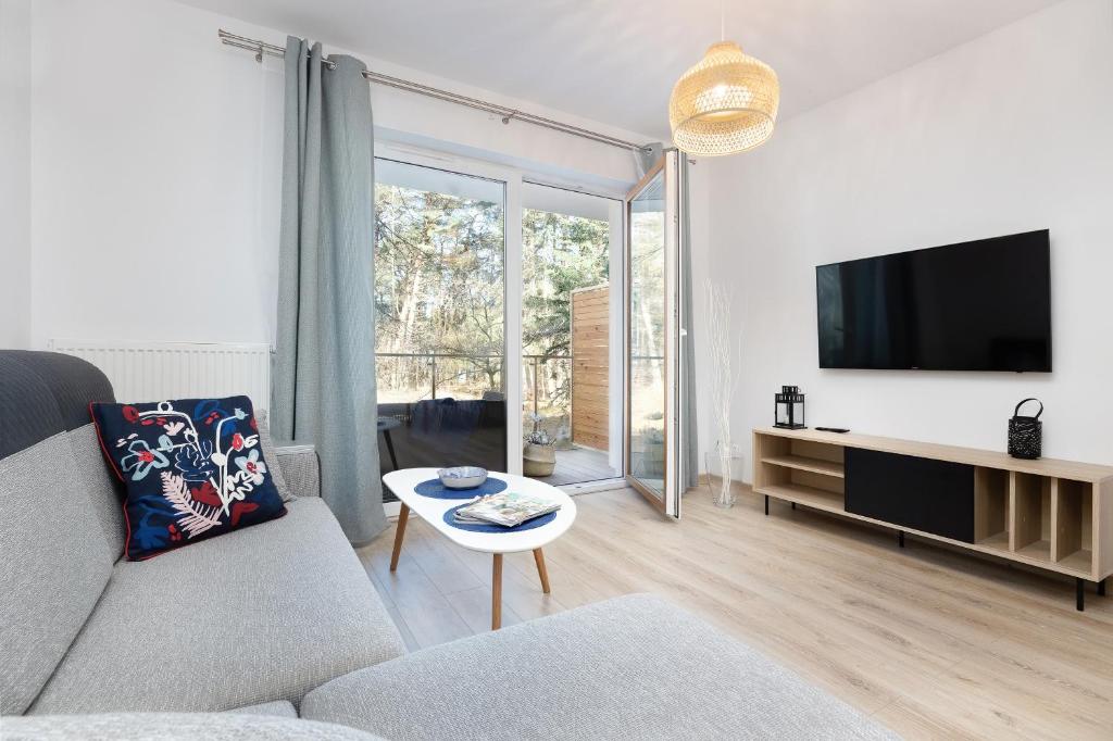 uma sala de estar com um sofá e uma televisão em Fabulous Apartments - Euronia em Pobierowo