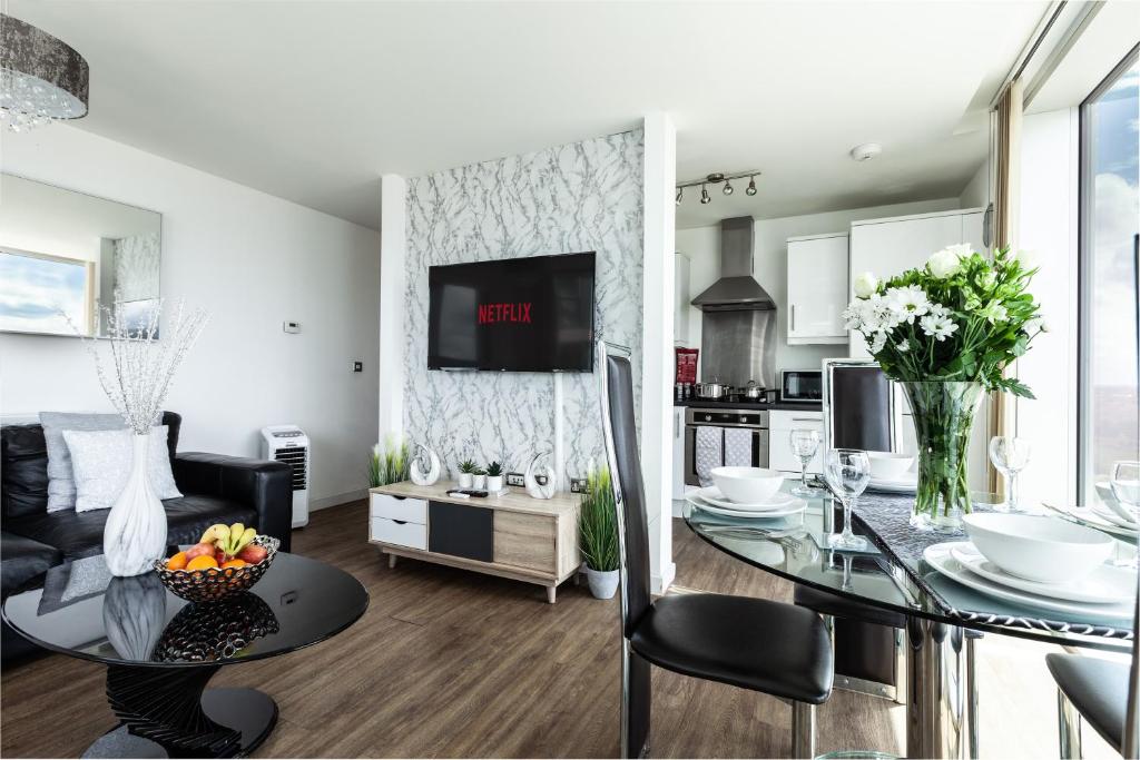 a living room with a dining room table and a kitchen at 2 Bedroom 2 Bathroom Apartment in Central Milton Keynes with Free Parking - Contractors, Relocation, Business Travellers in Milton Keynes