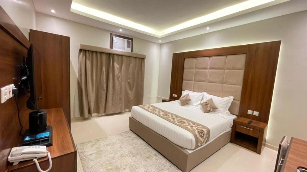 Habitación de hotel con cama, teléfono y TV en Rawaes Hotel, en Medina