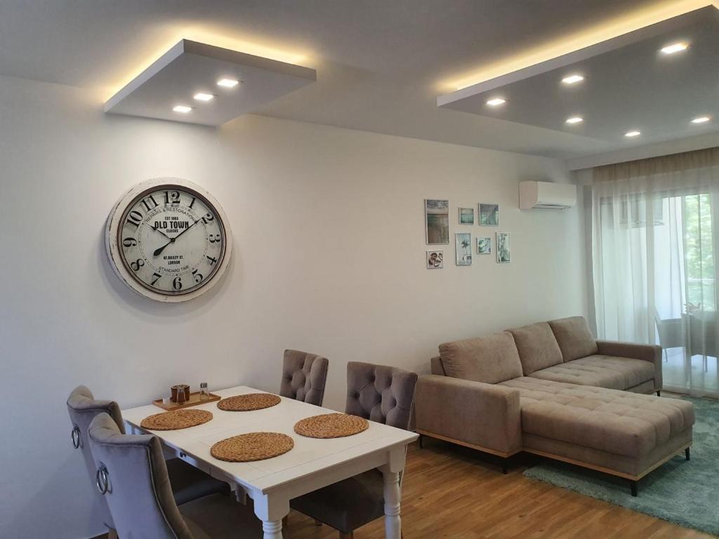 een woonkamer met een tafel en een klok aan de muur bij Sunshine Resort Turquoise Apartman in Zamárdi