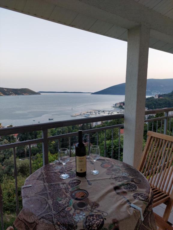 a table with a bottle of wine and glasses on a balcony at Apartman G 60 in Meljine