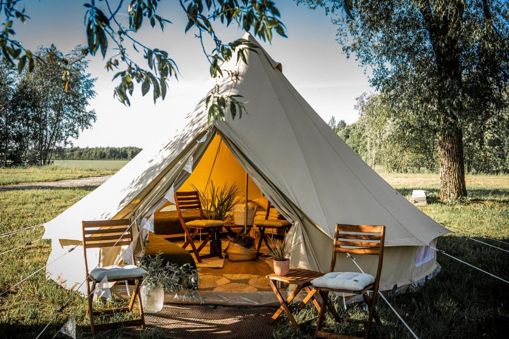 a tent with chairs and a table in a field at WPark Glamping in Põltsamaa