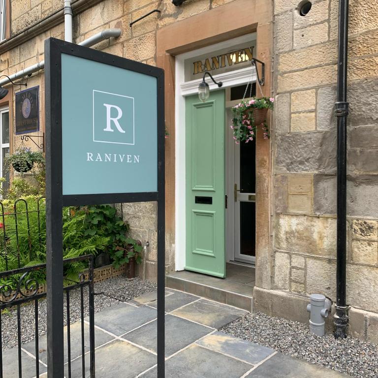 a sign in front of a building with a green door at Raniven in Oban