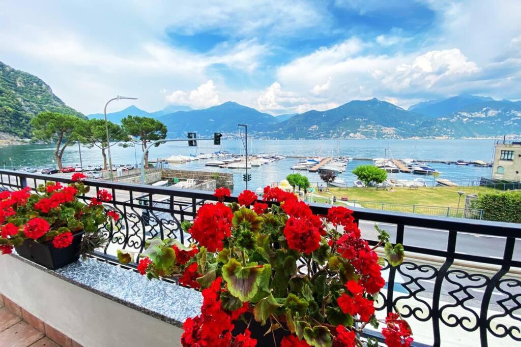 een balkon met rode bloemen en uitzicht op het water bij Casa Anna with Lake View in Menaggio