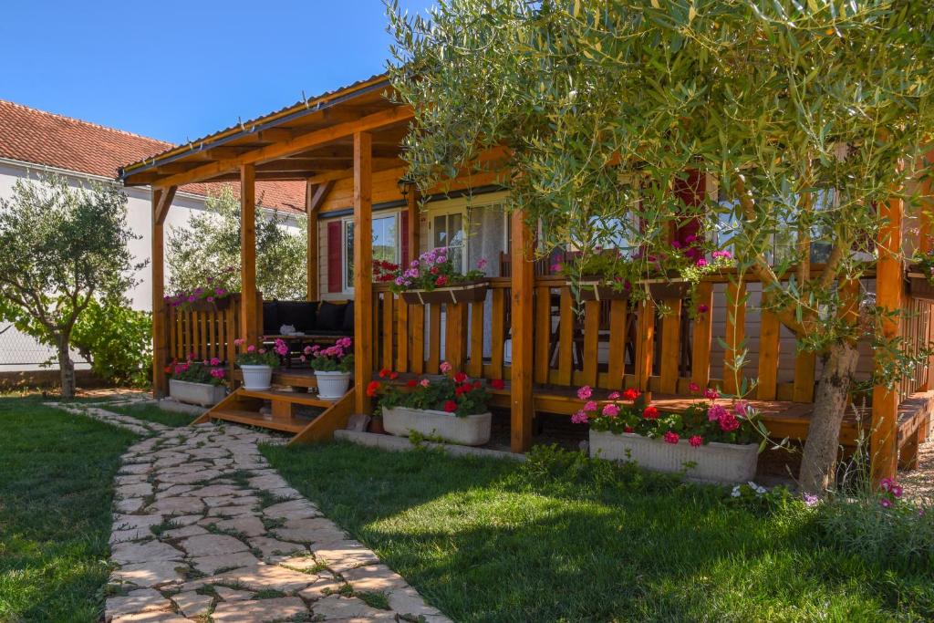 una casa in legno con piante in vaso e una recinzione di House Matea a Bilice (Bilizze)