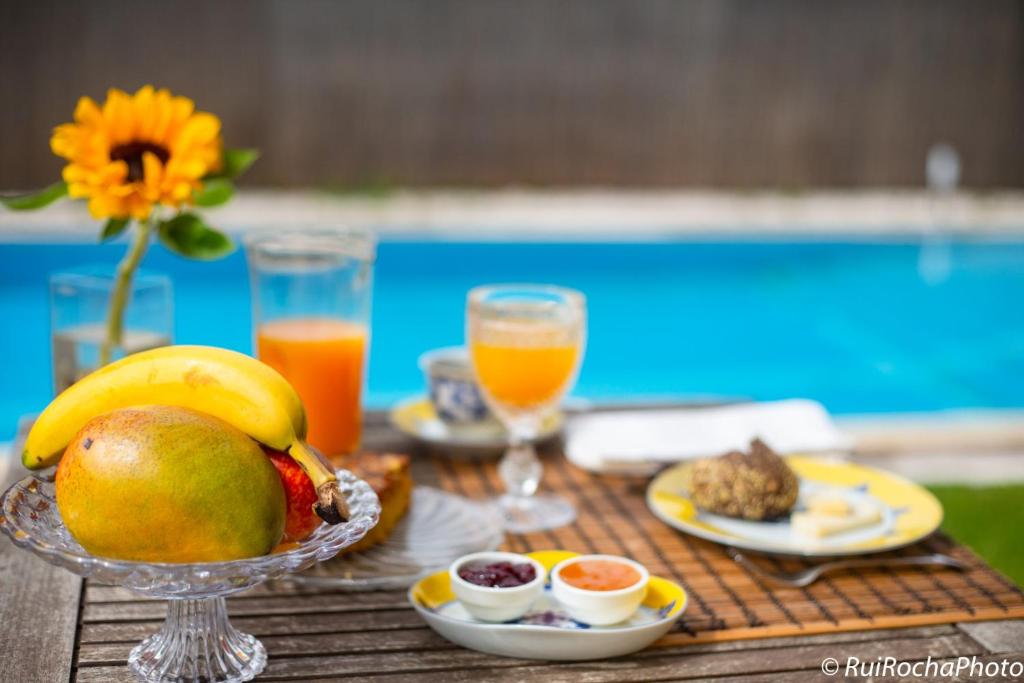 a table topped with a bowl of fruit and juice at Casa do Pinhal Guest House in Vila Chã