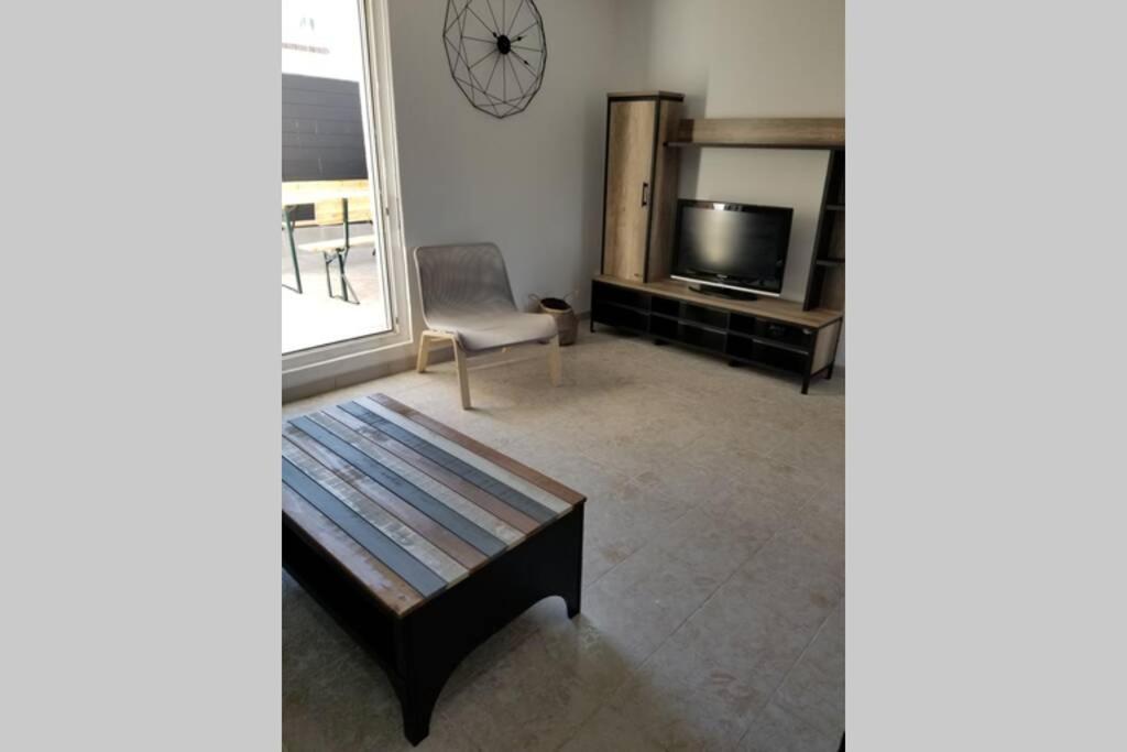 a living room with a table and a chair and a television at Calanques de Sormiou in Marseille