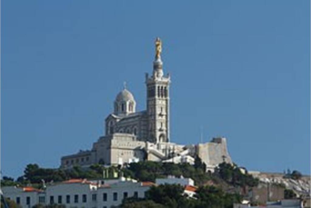 a building with a clock tower on top of a hill at Calanques de Sormiou in Marseille