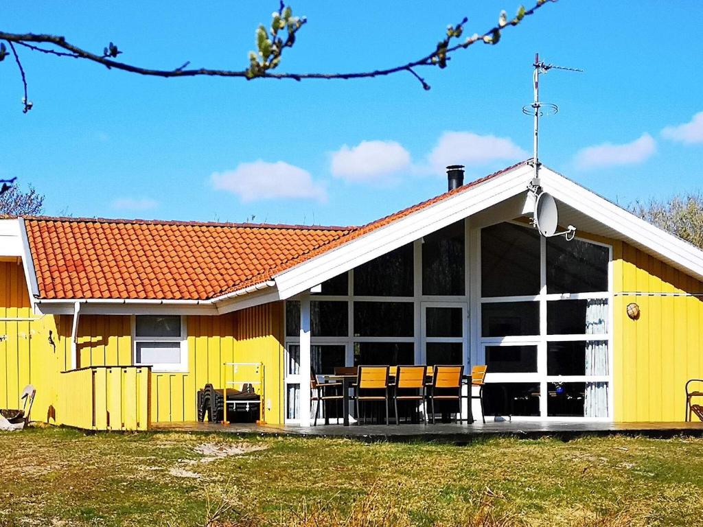a yellow building with chairs and tables in front of it at 10 person holiday home in Fan in Fanø