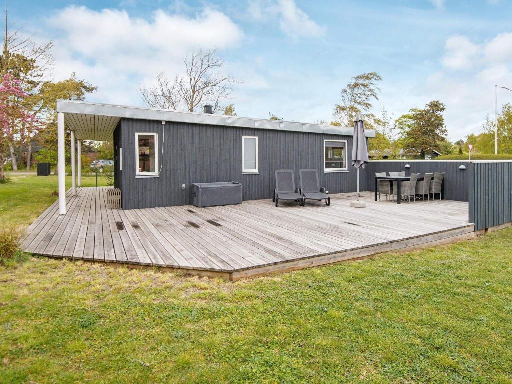 a tiny house with a deck in a yard at Holiday home Ebeltoft XXI in Ebeltoft