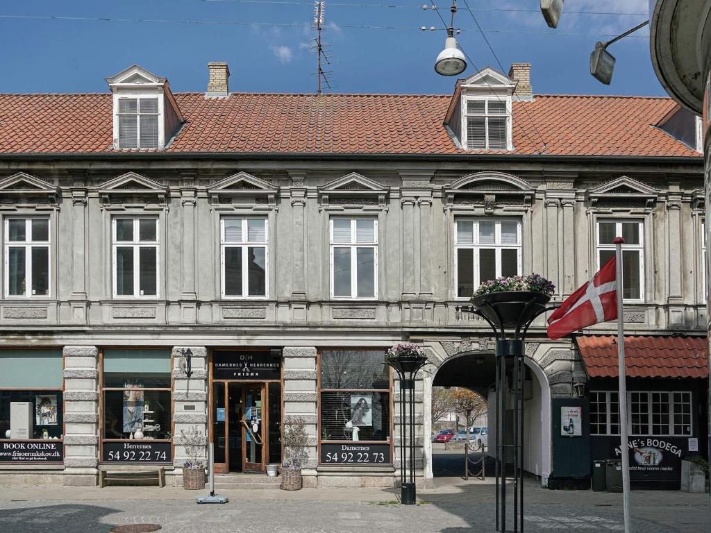 un antiguo edificio con una bandera delante de él en 4 person holiday home in Nakskov, en Nakskov