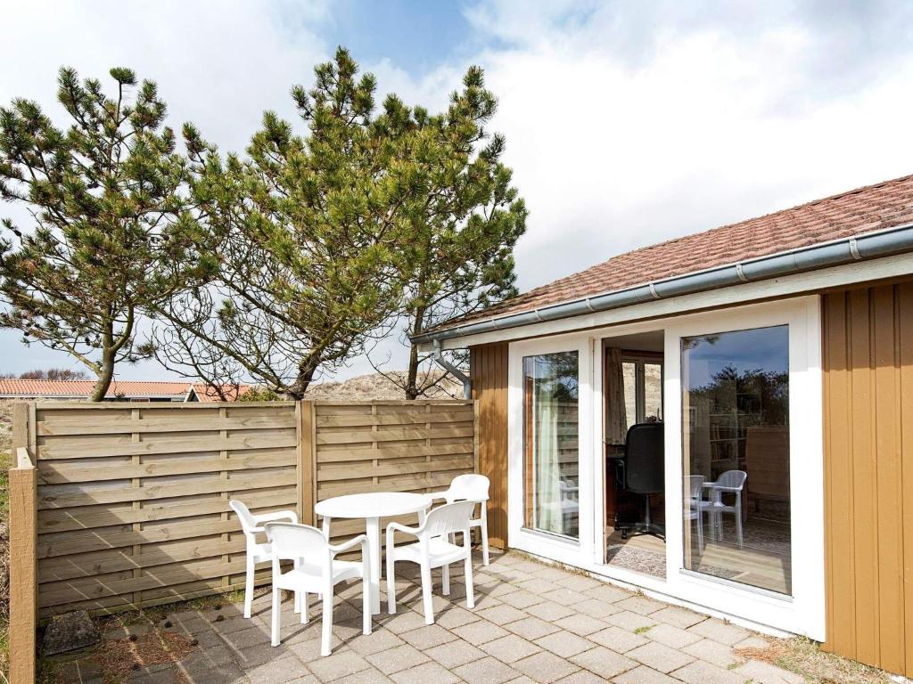 eine Terrasse mit einem Tisch, Stühlen und einem Zaun in der Unterkunft 5 person holiday home in Fan in Fanø