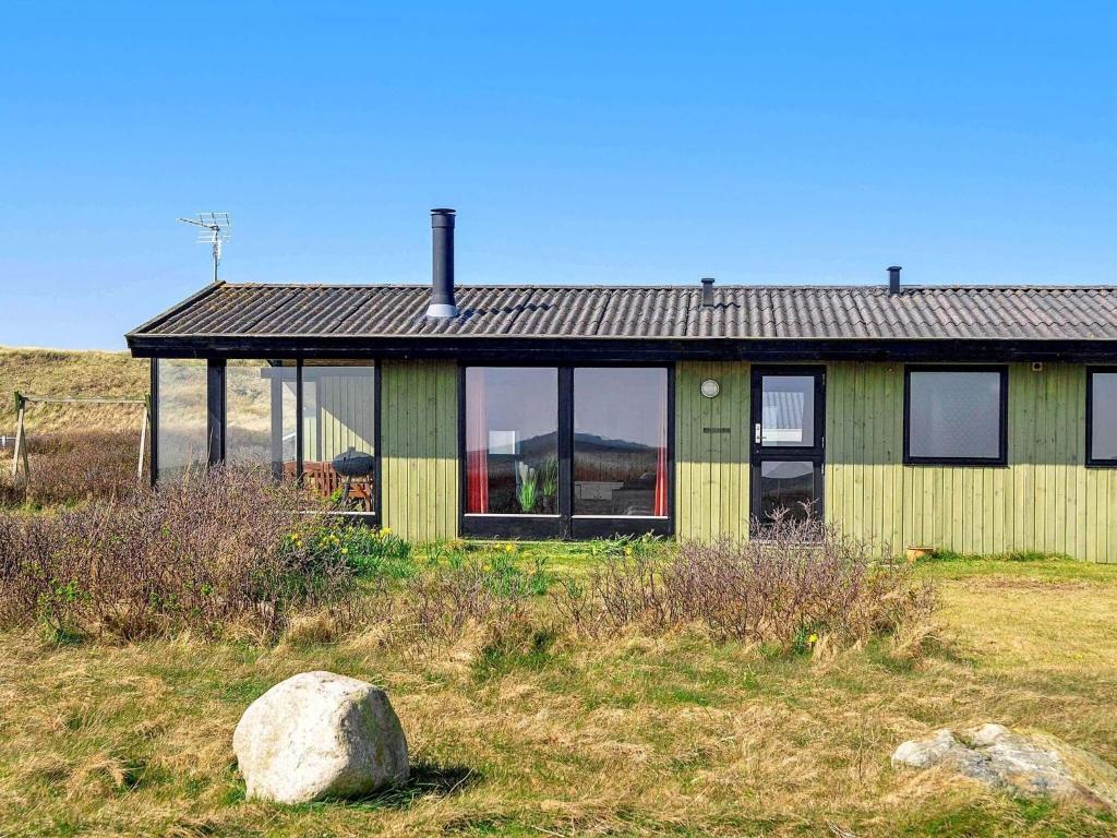 a house in a field with a rock in front of it at 5 person holiday home in Harbo re in Harboør