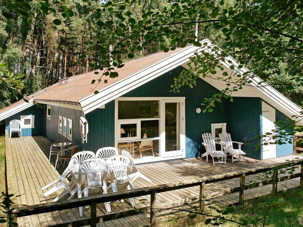 a blue house with chairs and tables on a deck at Quaint Holiday Home in Nex with Beach nearby in Vester Sømarken