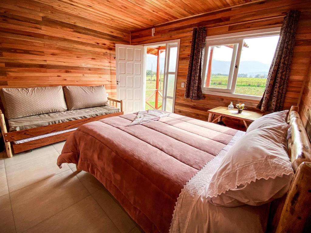 um quarto com uma cama, um sofá e janelas em Pousada Flor do Campestre em Urubici