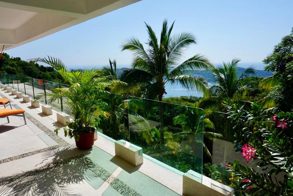 een balkon met uitzicht op de oceaan en palmbomen bij Mexican Condo by the sea in Acapulco