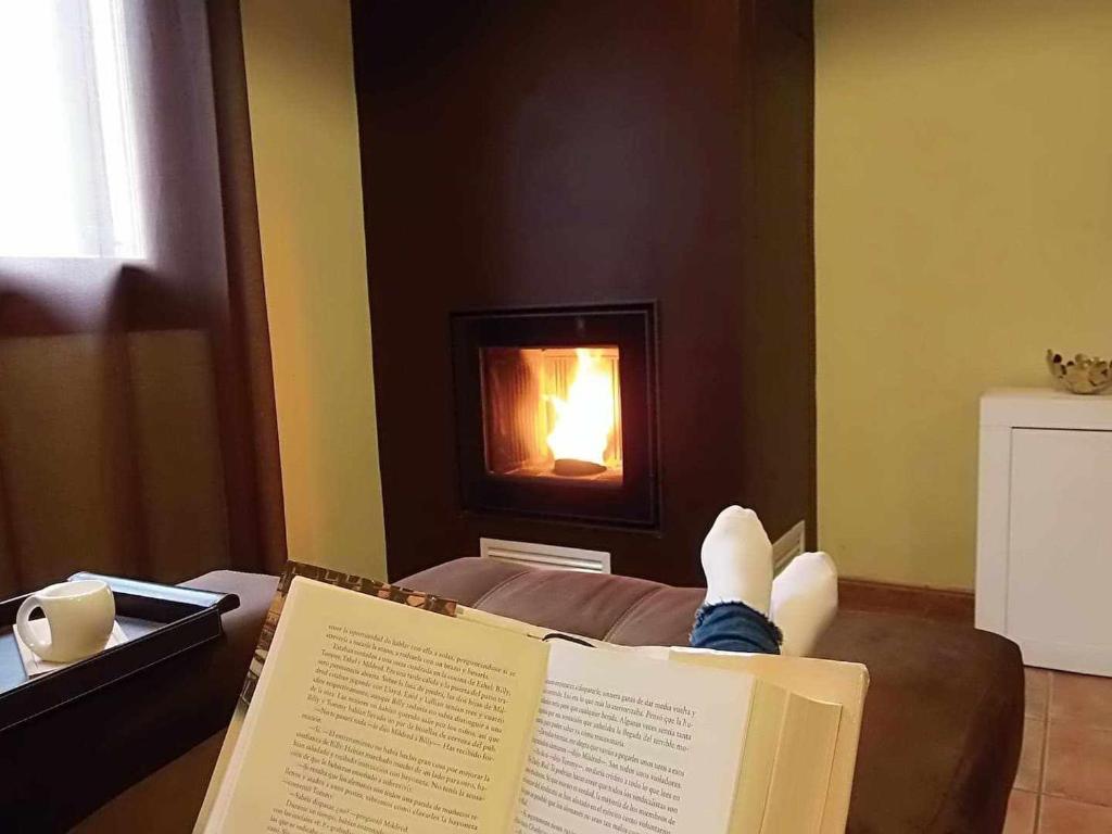 エチャラルにあるCasa iparraitz casa con encanto y hermoso jardínの暖炉の前で本を読んでいる人