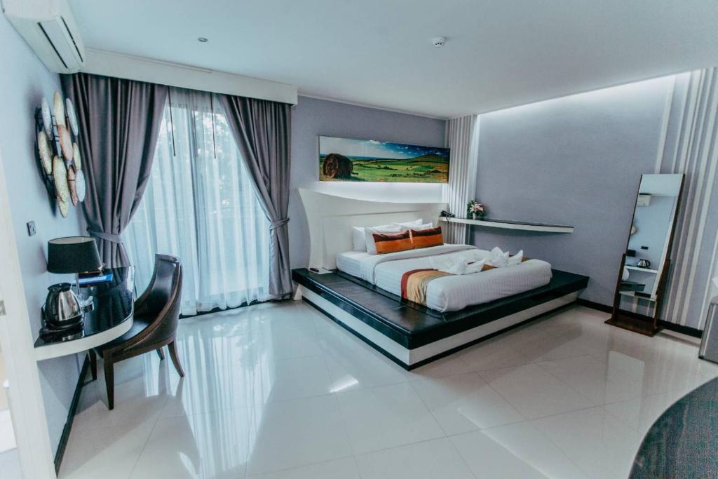 um quarto com uma cama, uma mesa e uma cadeira em Mantra Varee Hotel em Khon Kaen