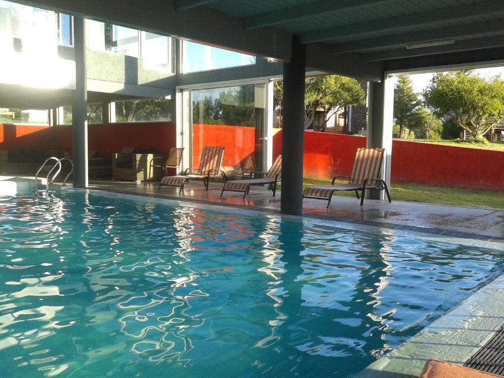 諾諾的住宿－Brisas de Nono，一座带椅子的游泳池,位于大楼旁