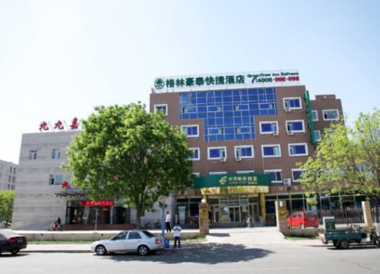 a building with a car parked in a parking lot at GreenTree Inn Beijing Shunyi South Shiyuan Street Express Hotel in Shunyi