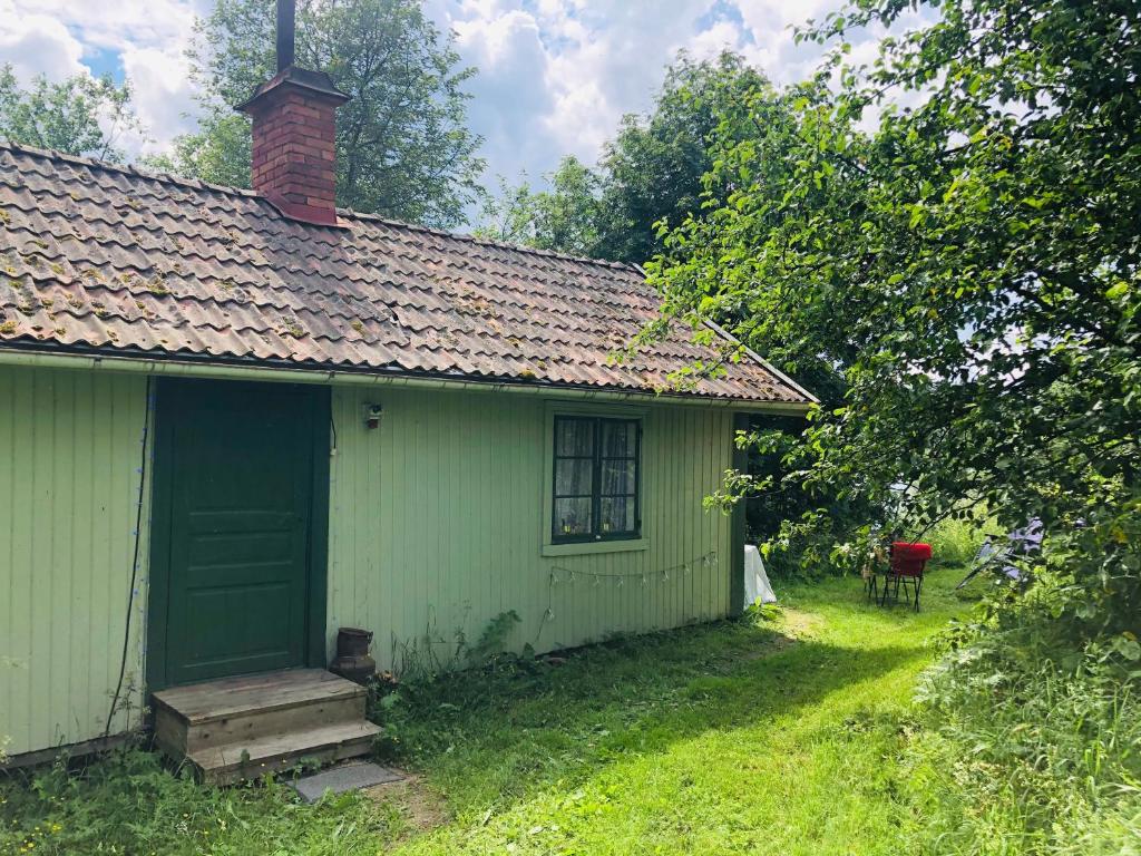 a green house with a red chair next to it at Fisherman s Cottage overlooking the river in Avesta