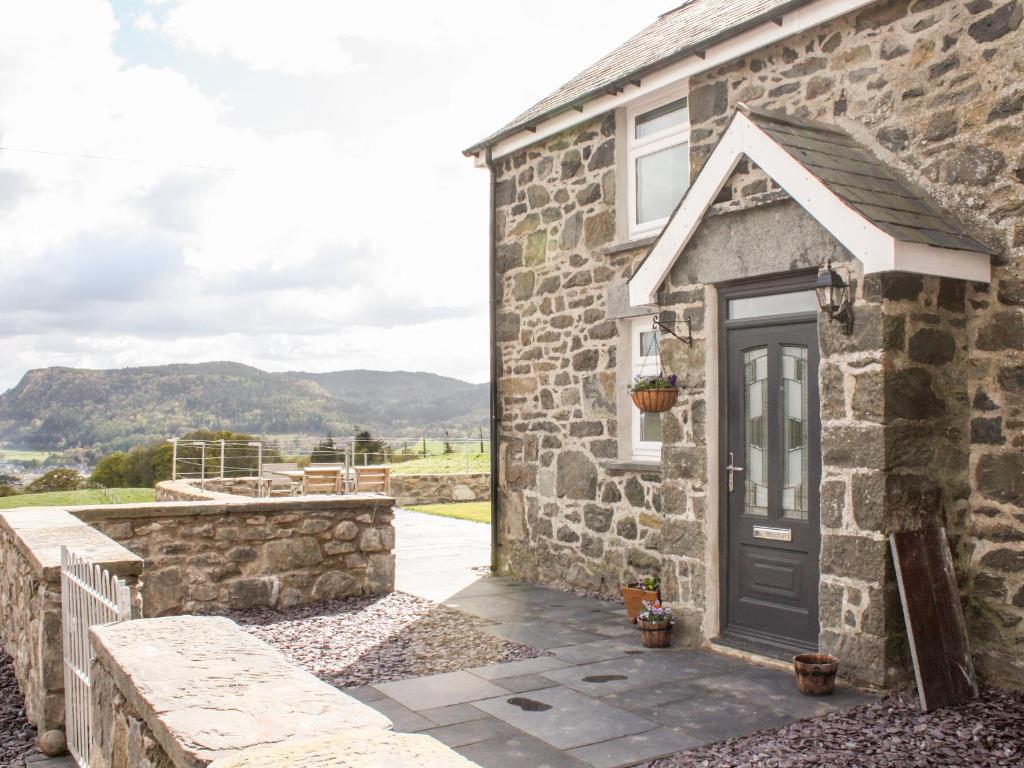 a stone house with a door and a patio at Pen Y Bryn Cottage in Llanddoget
