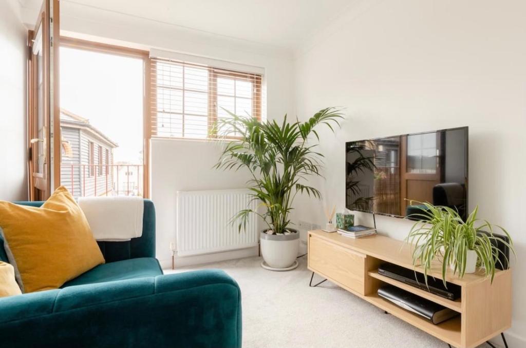 ein Wohnzimmer mit einem blauen Sofa und zwei Topfpflanzen in der Unterkunft Rose Mews Central Broadstairs in Kent
