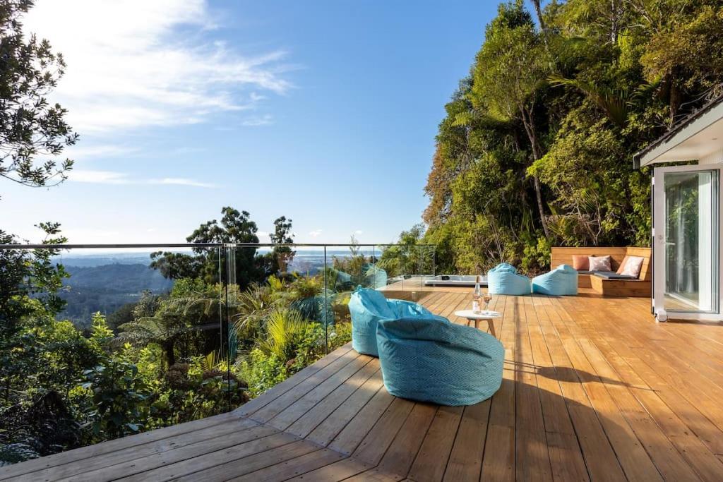 a wooden deck with blue furniture on top of a house at Tree-top luxury in the Waitakere Ranges in Auckland