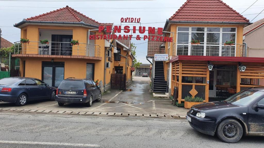 zwei Autos auf einem Parkplatz vor einem Gebäude geparkt in der Unterkunft PENSIUNE RESTAURANT OVIDIU in Valea lui Mihai