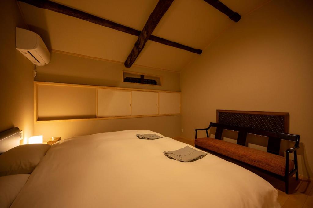 a bedroom with a large white bed and a bench at CAMPTON Higashiyama Roku in Kyoto