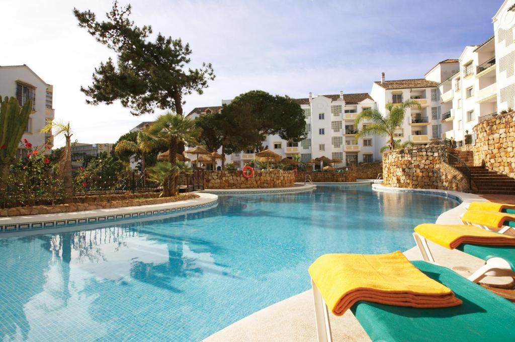 duży basen z krzesłami i budynkami w obiekcie Ona Alanda Club Marbella w Marbelli