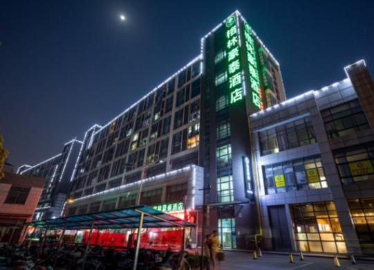 een groot gebouw met groene lichten erop bij GreenTree Inn JiangSu SuZhou SuZhouLeYuan TianPing College Business Hotel in Suzhou