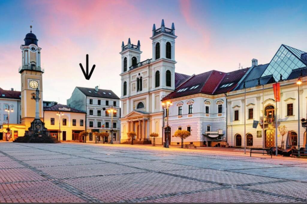 a city square with two towers and a clock tower at Apartmán pod Vežou 1 in Banská Bystrica