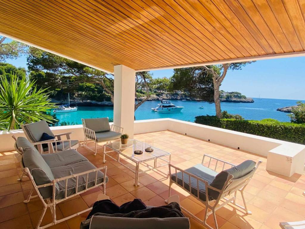 un patio con sillas y una mesa con vistas al agua en Villa Sa Pau, en Santanyí
