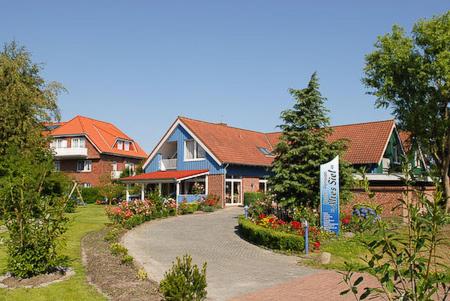 a house with a sign in the middle of a driveway at Hotel-Pension Altes Siel in Bensersiel